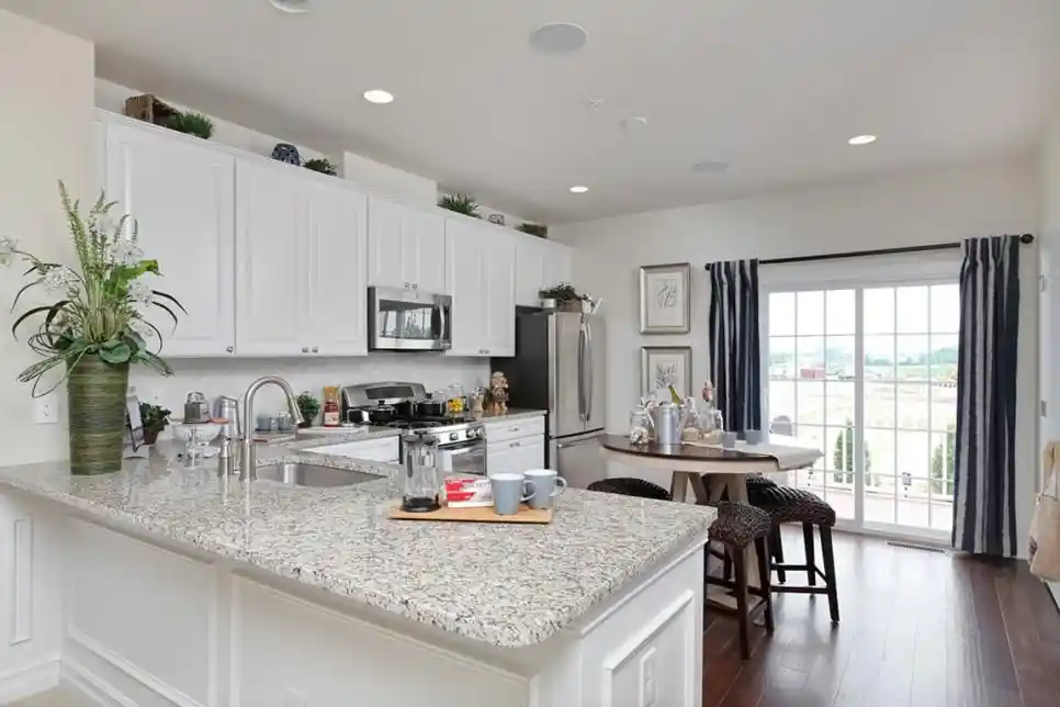 a large kitchen with white cabinets and granite countertop